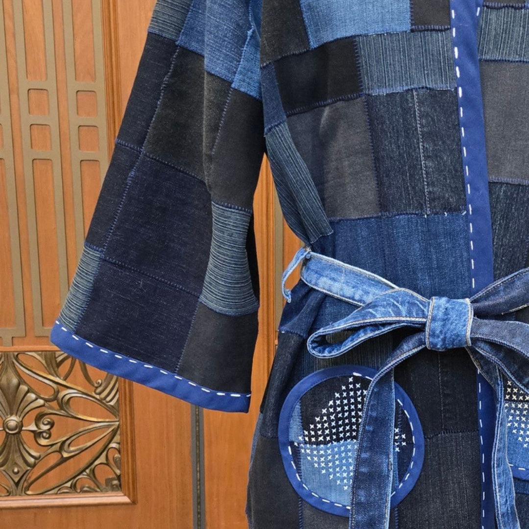 Patchwork denim coat with a belt against a wooden background